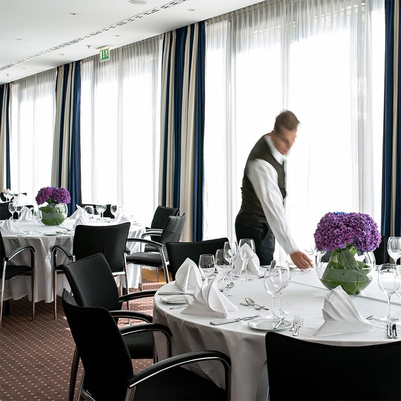 Eleganter Veranstaltungsraum mit Blumen und gedeckten Tischen.